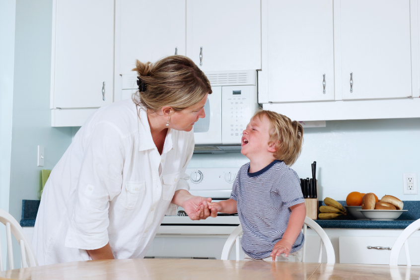 A mother trying to calm her crying toddler at home