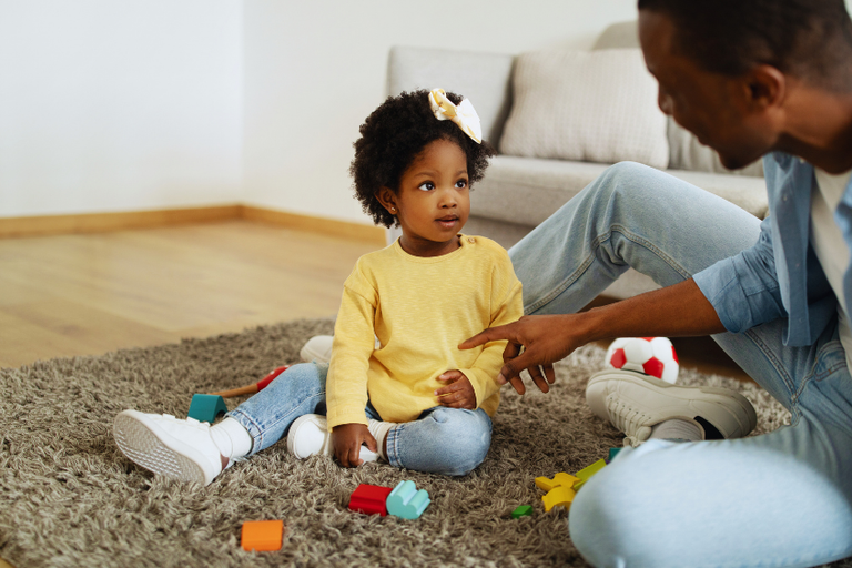 A father playing and talking to his toddler daughter