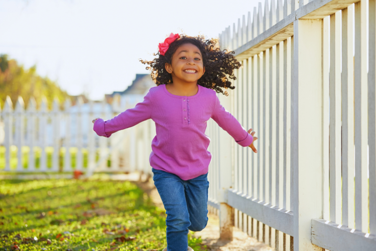 A young girl in pink sweater playing and running outdoors